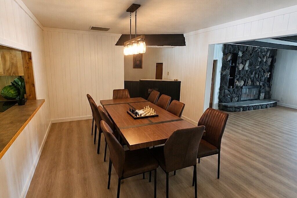 Un espace repas comprenant une table et des chaises en bois, un lustre et un mur en pierre.