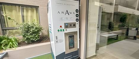 A vending machine with a water dispenser, located outside a building with a glass door.