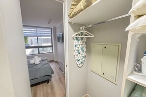 Ett litet sovrum med en säng, ett torkställ, en garderob och ett fönster med utsikt.