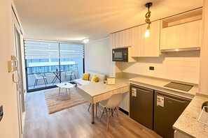 Eine moderne Küche mit Essbereich, ein Balkon mit Tisch und Stühlen sowie Blick auf die Stadt.