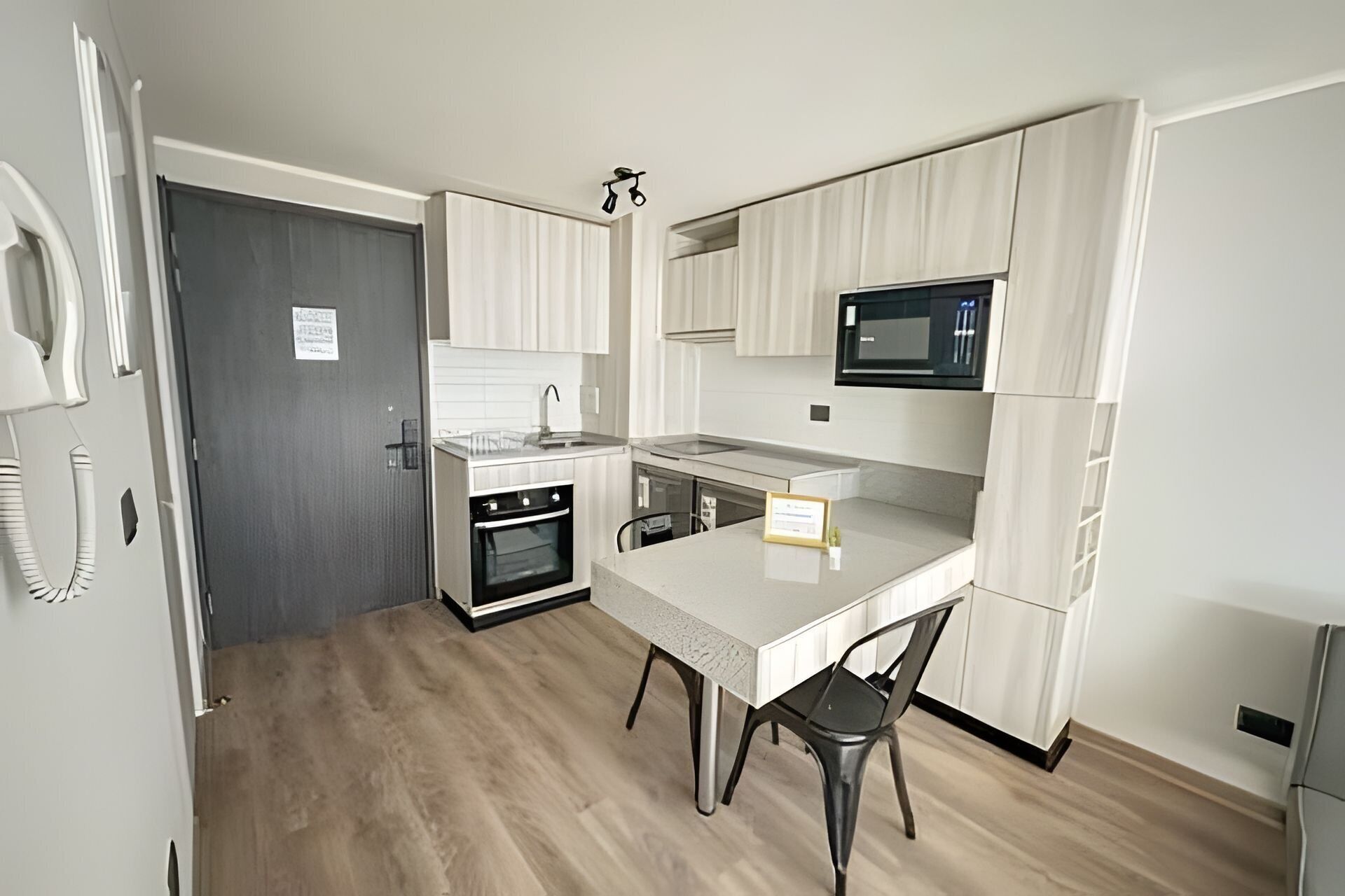 A compact kitchen with a microwave, oven, and sink.
