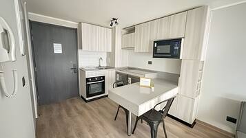 A compact kitchen with a microwave, oven, and sink.