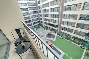 A high-rise building with multiple balconies, a courtyard with green artificial turf, and a view of adjacent buildings. - Modern apartment near the subway | portable Wi-Fi (Santiago)