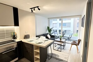 A modern kitchen with a dining area, a built-in oven, and a view of the outside. - Downtown apartment steps from Santander Arena (Santiago)