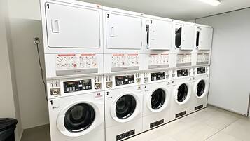 A laundry facility with multiple washing machines and dryers, each with a control panel and numbered for identification.