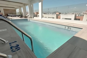 A swimming pool with a view of a cityscape, a lounge area with a table and chairs, and a poolside number 129. - Central apartment | Near Santander Arena | Wi-Fi (Santiago)