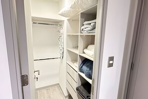 A walk-in closet with a hanging rod, shelves, and drawers. - Central boutique apartment steps from Movistar|WIFI (Santiago)