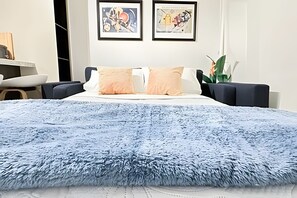 Une chambre à coucher avec un lit, deux œuvres d’art encadrées accrochées au mur et un bureau avec une chaise.