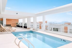 A modern indoor pool with clear glass walls, lounge chairs, and potted plants. - Central boutique apartment close to Santander Arena (Santiago)