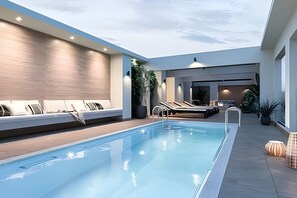 Ett modernt inomhuspoolområde med en lounge, sittplatser och utsikt över himlen.