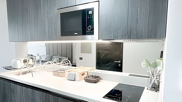 A modern kitchen with a microwave, toaster, and a built-in induction cooktop. - Contemporary, comfortable apartment with WiFi and air conditioning (Santiago)