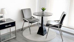 A modern room with a round table, two chairs, a small potted plant, a lamp, and a desk with drawers. - Contemporary, comfortable apartment with WiFi and air conditioning (Santiago)