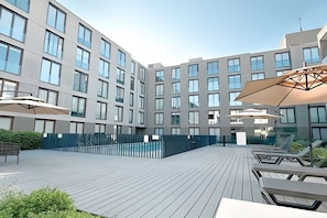 A modern building with a courtyard featuring outdoor seating and umbrellas. - Contemporary, comfortable apartment with WiFi and air conditioning (Santiago)