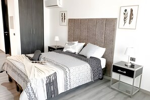A modern bedroom with a bed, bedside tables, a lamp, and artwork on the walls. - Contemporary, comfortable apartment with WiFi and air conditioning (Santiago)