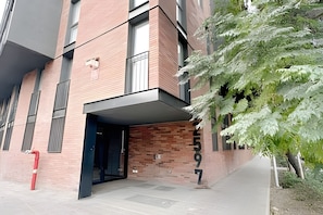 Een modern gebouw met een bakstenen gevel, een glazen ingang en een zichtbaar huisnummer.