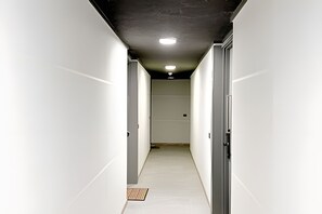 A narrow hallway with white walls, a wooden floor, and a ceiling with recessed lighting. - Modern, cozy apartment with WiFi and air conditioning (Santiago)