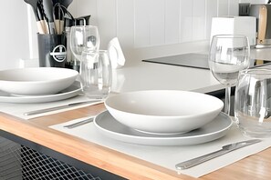 A modern kitchen with white appliances, a dining table set with white plates and bowls, and a water pitcher. - Modern, cozy apartment with WiFi and air conditioning (Santiago)