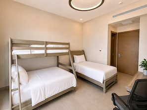 Una habitación con dos literas, un escritorio y una silla, además de una puerta.