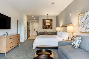 A hotel room with a bed, a sofa, a TV, a desk, and a bathroom visible in the background. - Gondola Right Outside - Westin Riverfront 2-Bedroom Villa (Avon)