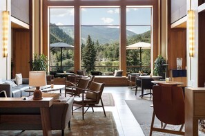 A spacious indoor area with large windows offering a mountain view, furnished with leather chairs and tables, and equipped with a bar area. - Gondola Right Outside - Westin Riverfront 2-Bedroom Villa (Avon)