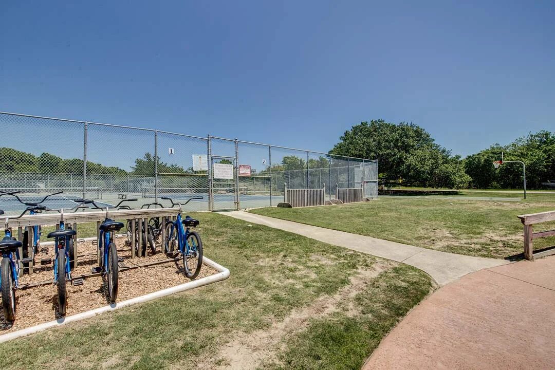 A fenced outdoor area with bicycles and a concrete path.