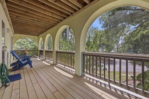 A covered porch with wooden flooring, a railing, and a view of trees and a road. - Ultra Classic | Private Pool, Hot Tub, and Community Pool (Corolla)