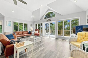 A spacious living room with a large window, a fireplace, and a comfortable seating area. - Ultra Classic | Private Pool, Hot Tub, and Community Pool (Corolla)