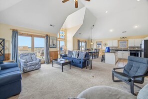 Ein geräumiges Wohnzimmer mit hohen Decken, einem Essbereich und einer Küche mit Blick.