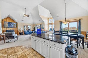 A spacious living area with a kitchen island, dining table, and seating. - Avalon Alibi | 300 ft to the beach | Private Pool, Hot Tub, and Pool Table (Kill Devil Hills)