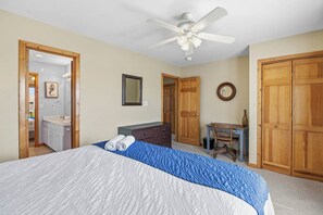 Ein Schlafzimmer mit Bett, Schreibtisch, Stuhl, Kleiderschrank und Deckenventilator.