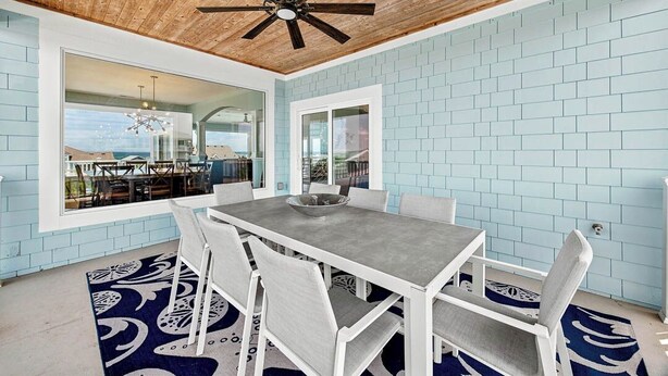 A dining area with a table and chairs, a ceiling fan, and a view through a glass door. - Sea To Sound | 740 ft to the beach | Private Pool, Hot Tub, and Dog Friendly (Duck)