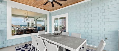 A dining area with a table and chairs, a ceiling fan, and a view through a glass door.