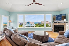 A living room with a large window, a fireplace, and a television. - Sea To Sound | 740 ft to the beach | Private Pool, Hot Tub, and Dog Friendly (Duck)