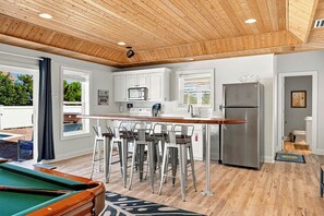 A modern kitchen with a bar area, wooden ceiling, and a pool table. - Sea To Sound | 740 ft to the beach | Private Pool, Hot Tub, and Dog Friendly (Duck)