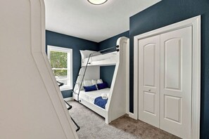 Ein Schlafzimmer mit Etagenbett, einer weißen Tür und einem Fenster mit Jalousien.