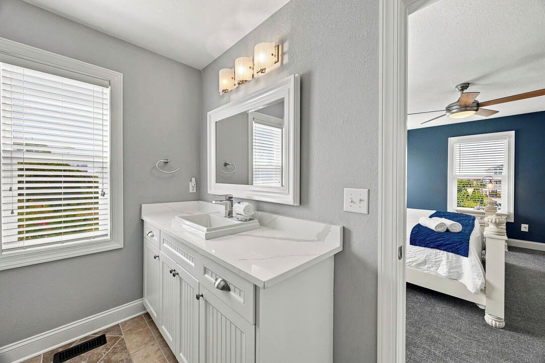 A bathroom with a white vanity, a mirror, and a ceiling fan.