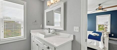A bathroom with a white vanity, a mirror, and a ceiling fan.