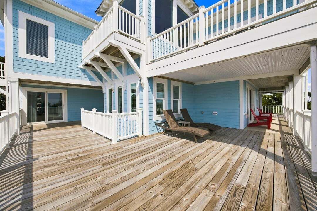 A two-story building with a wooden deck, a balcony, and a covered porch area.