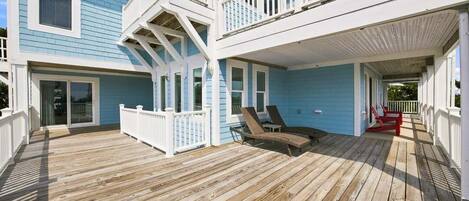 A two-story building with a wooden deck, a balcony, and a covered porch area.