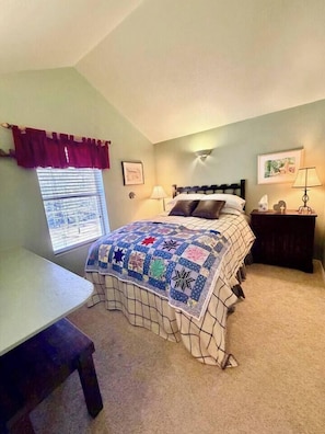 A bedroom with a bed, bedside table, lamp, and a window with curtains. - “Peace of the Mountains” (Cloudcroft)