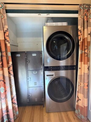 A laundry room with two stacked washing machines and a metal utility cabinet. - “Peace of the Mountains” (Cloudcroft)
