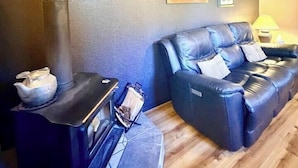 Ein Zimmer mit einer Couch, einem kleinen Tisch mit Wasserkocher und einem Kamin.