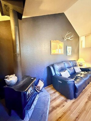 A room with a sofa, a small table with a kettle, and a fireplace. - “Peace of the Mountains” (Cloudcroft)
