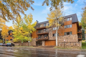 A modern multi-story building with a stone facade, wooden balconies, and a garage door. - Southpoint Aspen Haven with A/C, Garage Parking, Ski Locker & Walkable Gondola Access (Aspen)