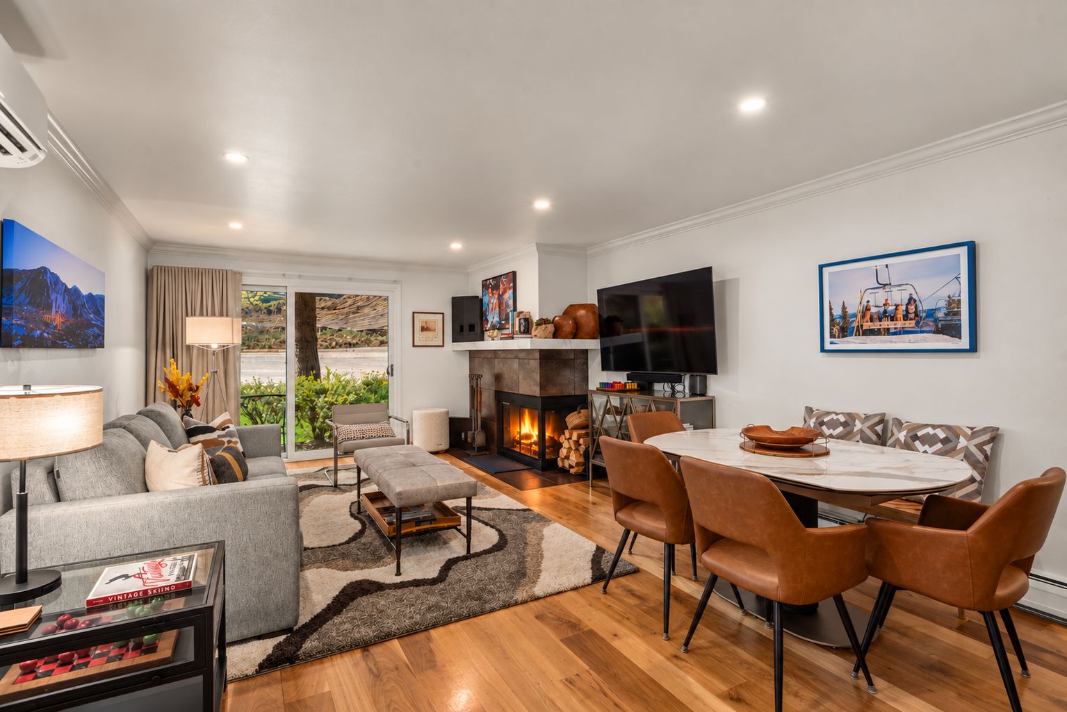Una sala de estar moderna con chimenea, un comedor y un televisor montado en la pared.