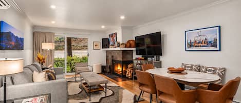Una sala de estar moderna con chimenea, un comedor y un televisor montado en la pared.