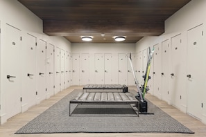 A row of white lockers with numbers, a bench, and skis leaning against the wall. - Southpoint Aspen Haven with A/C, Garage Parking, Ski Locker & Walkable Gondola Access (Aspen)