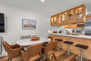 A modern kitchen with a marble island, wooden cabinets, and bar stools. - Southpoint Aspen Haven with A/C, Garage Parking, Ski Locker & Walkable Gondola Access (Aspen)