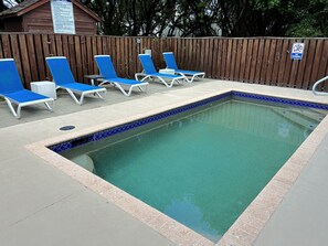 Ein Pool mit blauen Liegestühlen und einem Holzzaun.