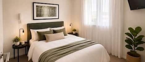 A neatly arranged bedroom with a bed, bedside tables, a wall-mounted TV, and a window with curtains.
